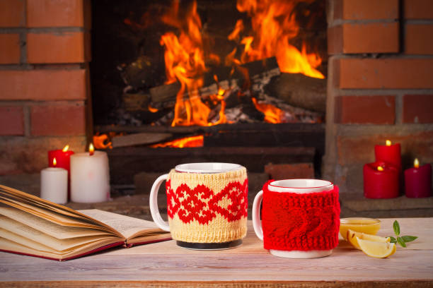 istock Hot drinks in mugs on wooden table beside cosy open fire place 875161662