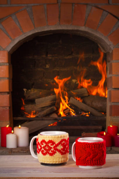 istock Hot drinks in mugs on wooden table beside cosy open fire place 875162504