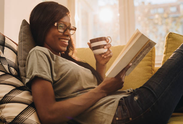 istock Happy black woman reading a book during coffee time at home. 875164986