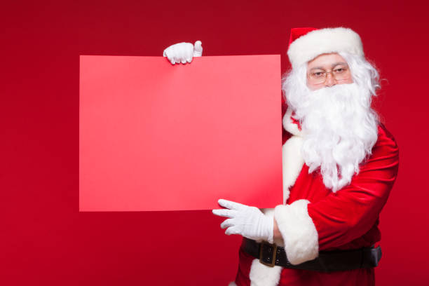 istock Santa Claus pointing in blank advertisement banner isolated on red background with copy space red leaf 875171998
