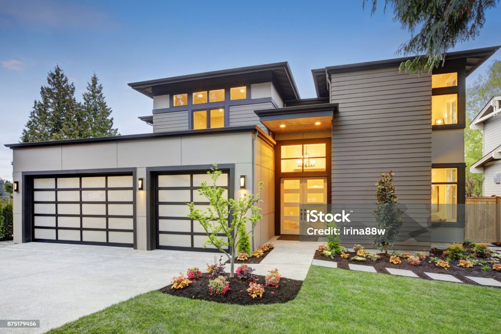 Luxurious new construction home in Bellevue, WA Luxurious new construction home in Bellevue, WA. Modern style home boasts two car garage spaces with glass folding doors illuminated by scones. Northwest, USA Modern Stock Photo