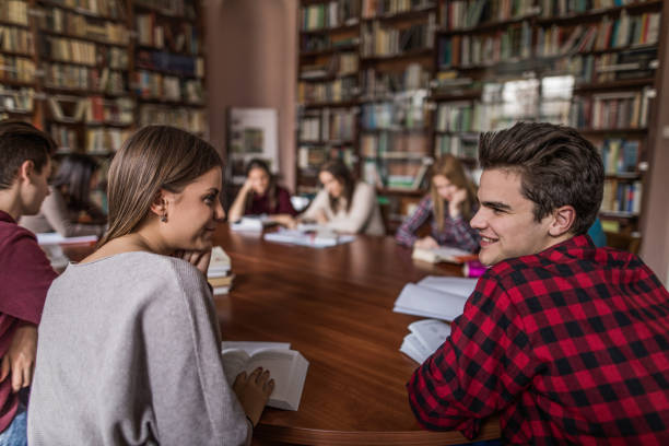 istock Smiling students talking to each other in the library. 875186406