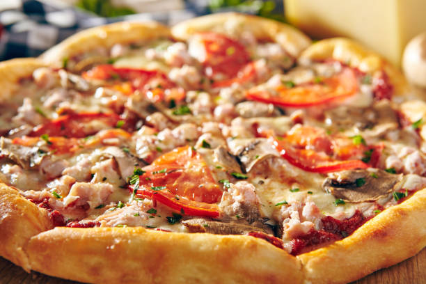 istock Pizza Restaurant Menu - Delicious Fresh Pizza with Mushrooms, Tomatoes and Meat. Pizza on Rustic Wooden Table with Ingredients 875191230