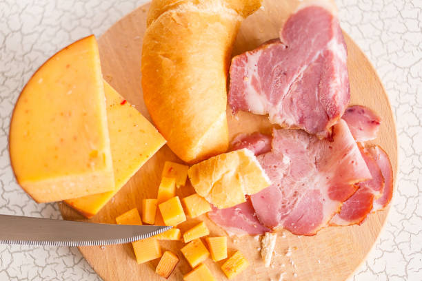 istock Ham, cheese, bread and salt on a wooden cutting board. 875194878