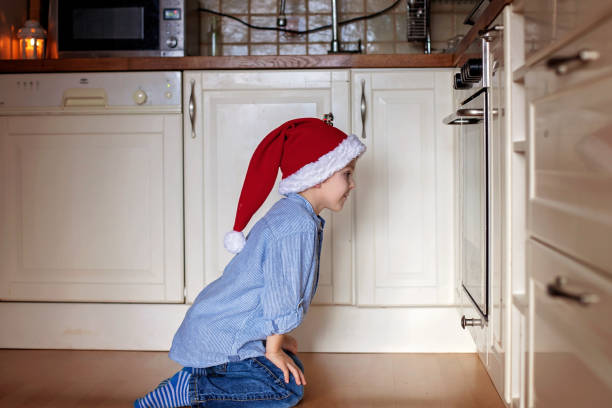 istock Curious little boy, watching ginger bread cookies in the oven 875195240