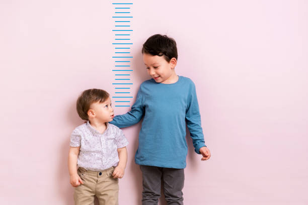 Child measuring his height Child measuring his height on wall. He is growing up so fast. boy height measure stock pictures, royalty-free photos & images