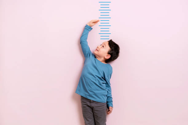 Child measuring his height Child measuring his height on wall. He is growing up so fast. boy height measure stock pictures, royalty-free photos & images