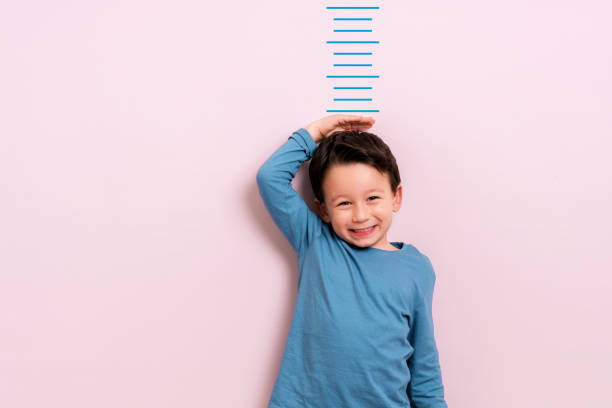 Child measuring his height Child measuring his height on wall. He is growing up so fast. boy height measure stock pictures, royalty-free photos & images