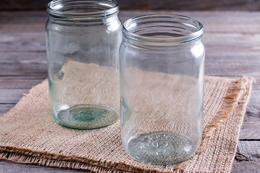 Empty canning jars await use on a wooden table