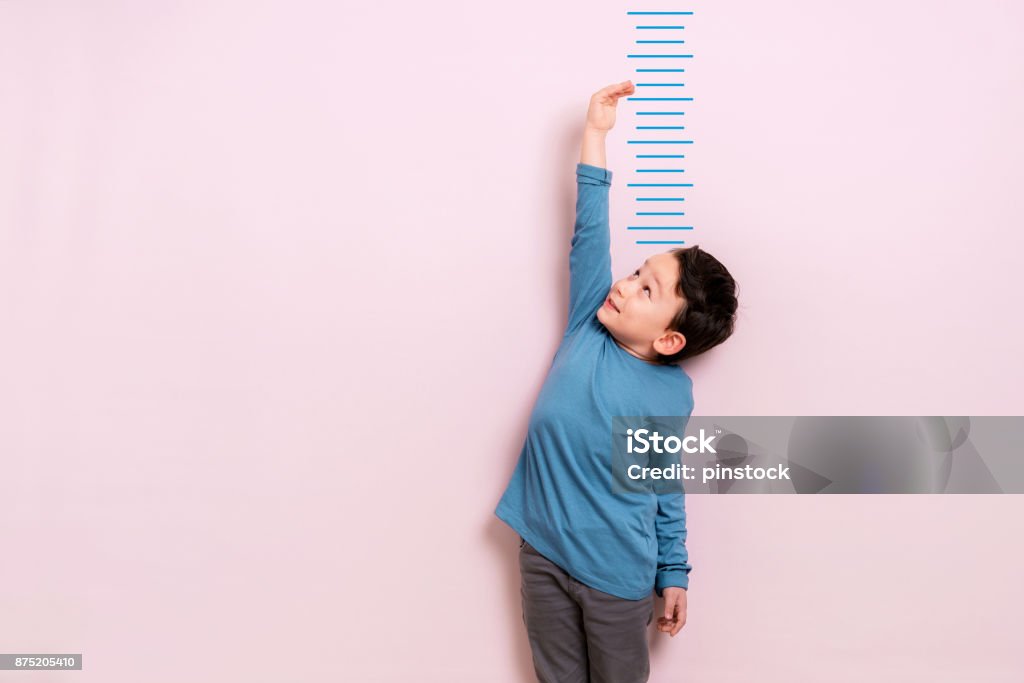 Child measuring his height Child measuring his height on wall. He is growing up so fast. Child Stock Photo