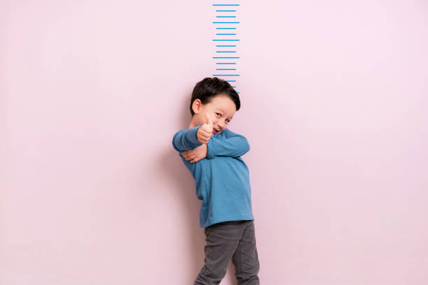 Child measuring his height Child measuring his height on wall. He is growing up so fast. boy height measure stock pictures, royalty-free photos & images