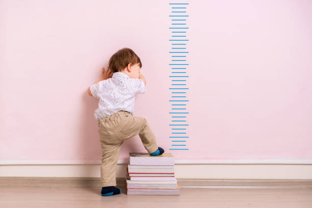 Child measuring his height Child measuring his height on wall. He is growing up so fast. boy height measure stock pictures, royalty-free photos & images