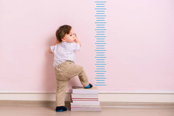 Child measuring his height Child measuring his height on wall. He is growing up so fast. boy height measure stock pictures, royalty-free photos & images