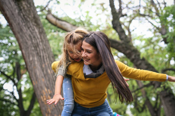 istock Mother carrying daughter on piggyback. On the move. 875205964