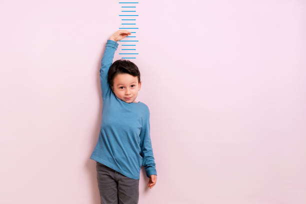 Child measuring his height Child measuring his height on wall. He is growing up so fast. boy height measure stock pictures, royalty-free photos & images
