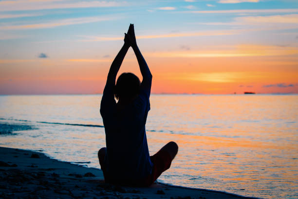 istock Silhouette of young man doing yoga at sunset 875205998