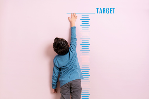 Child measuring his height on wall. He is growing up so fast.