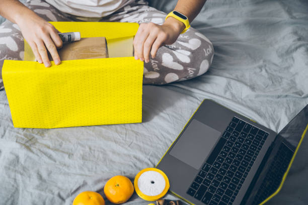 istock woman wrapping present in top yellow paper 875214236