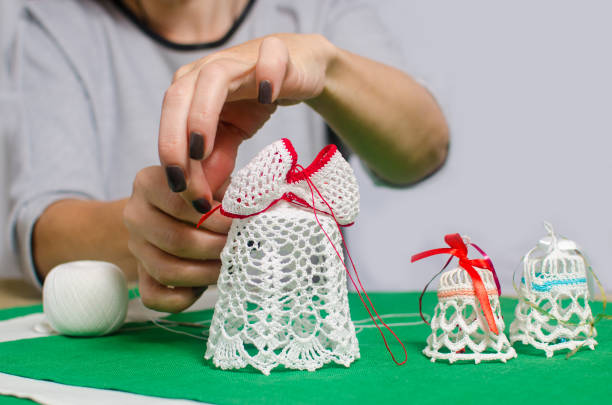 istock woman doing a bow on a Christmas handmade nitted bell 875218184