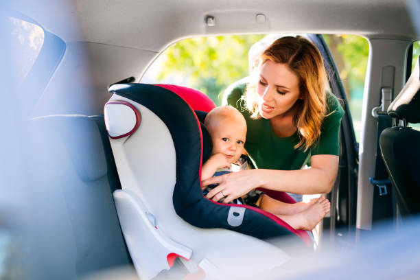 young mother putting baby boy in the car seat. - car baby baby car seat child imagens e fotografias de stock