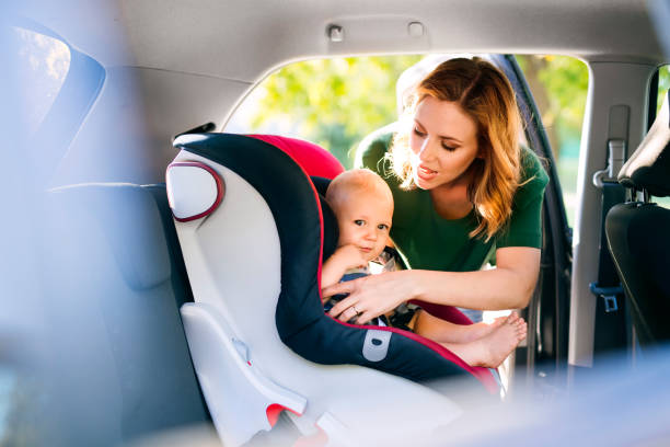 年輕的母親把男嬰放在汽車座椅上。 - 嬰兒安全座椅 圖片 個照片及圖片檔