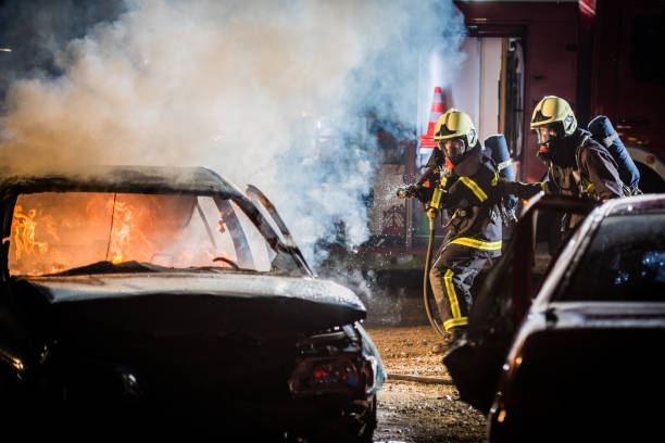istock Firefighters spraying water on burning car 875228710