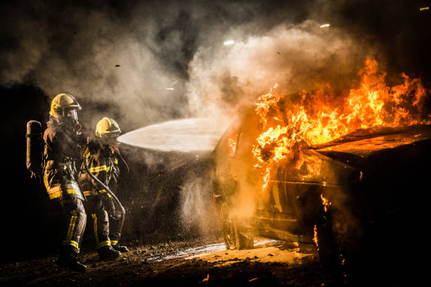 istock Firefighters spraying water on burning car 875228730