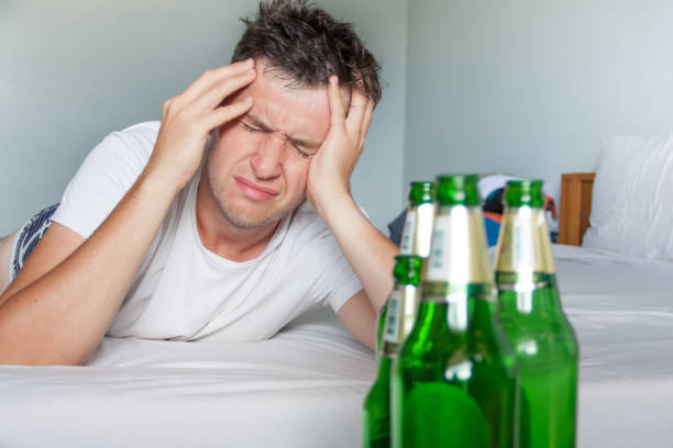 Hangover suffering man close up portrait with bottles of beer. stock photo