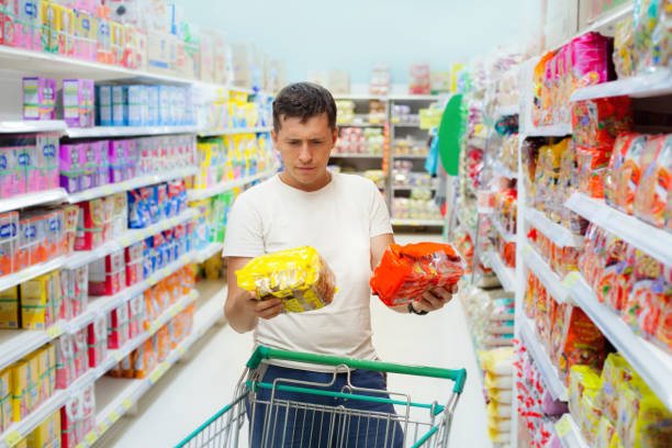 joven caucásica que elegir entre dos productos similares. - supermarket shopping retail choice fotografías e imágenes de stock