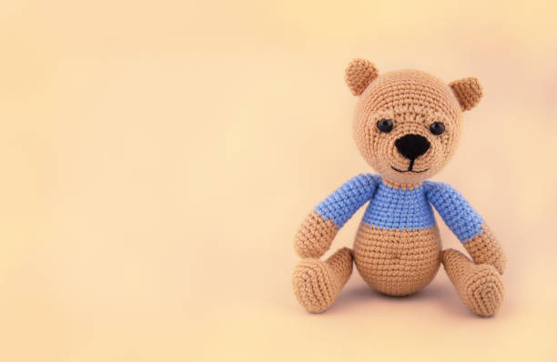 istock Little crocheted teddy bear on a gentle yellow background. Soft toy handmade. Copy space 875233946