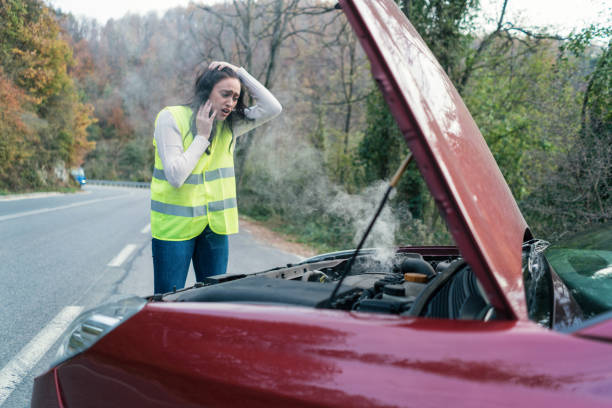 istock Young stressed woman looking at her broken down car 875234550