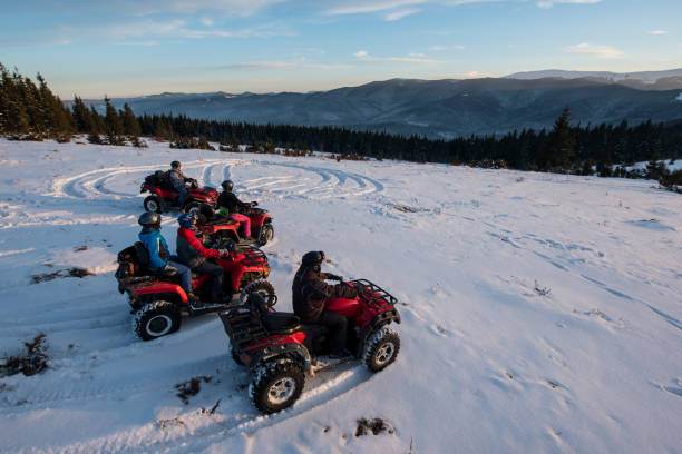 group of people sitting on off-road four-wheelers atv bikes in the the mountains in winter evening - off road vehicle snow 4x4 driving imagens e fotografias de stock