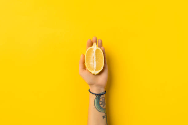 cropped image of woman holding half of lemon isolated on yellow