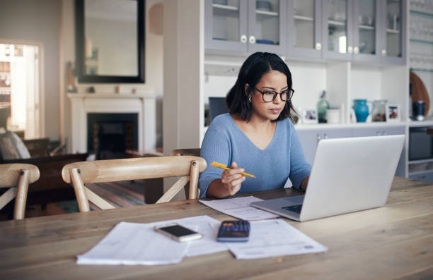 Her home is a place for productivity Shot of a young woman using a laptop while working from home online education stock pictures, royalty-free photos & images