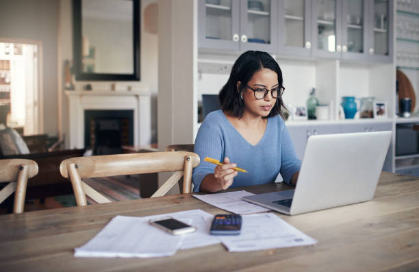 Her home is a place for productivity Shot of a young woman using a laptop while working from home e learning stock pictures, royalty-free photos & images