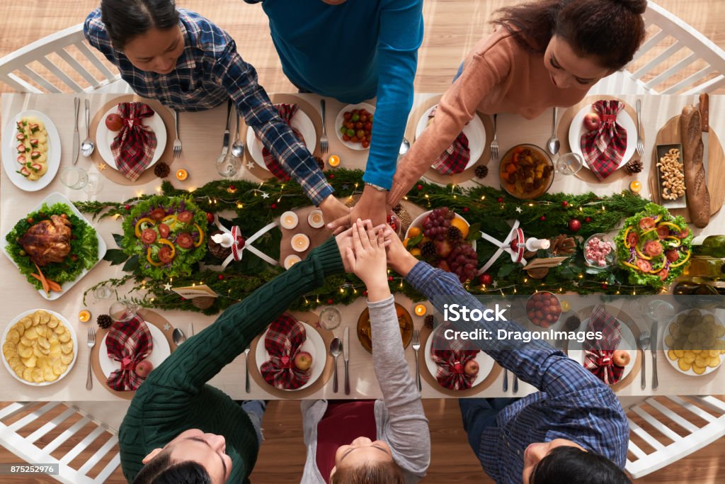 Dinner together Hands of people stacking hands stacking hands over dinner table Above Stock Photo