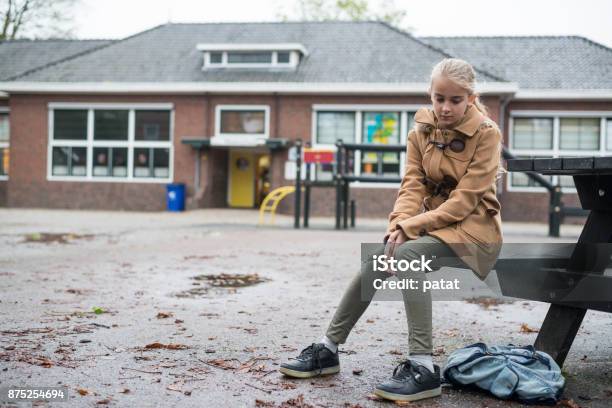 Sad Girl Sitting At Schoolyard Stock Photo - Download Image Now - Child, Loneliness, School Building