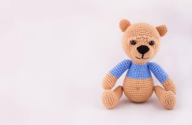 istock Little crocheted teddy bear on a gray background. Soft toy handmade. Copy space 875254986