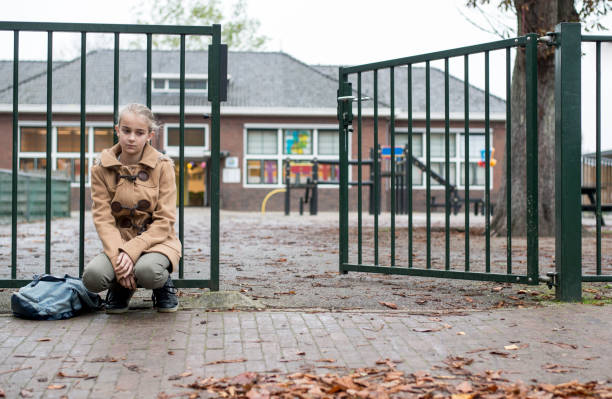 istock Sad girl sitting at school gate alone 875255092