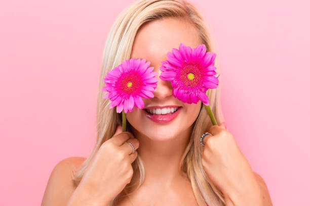 Young woman with pink garberas on a pink background