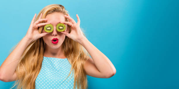 istock Happy young woman holding kiwis 875255396