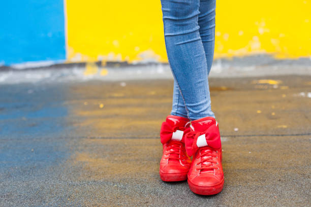 Woman in red sneakers against yellow and blue wall