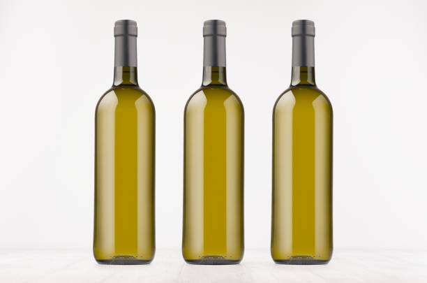 istock Three green wine bottles with white wine on white wooden board, mock up. 875261528