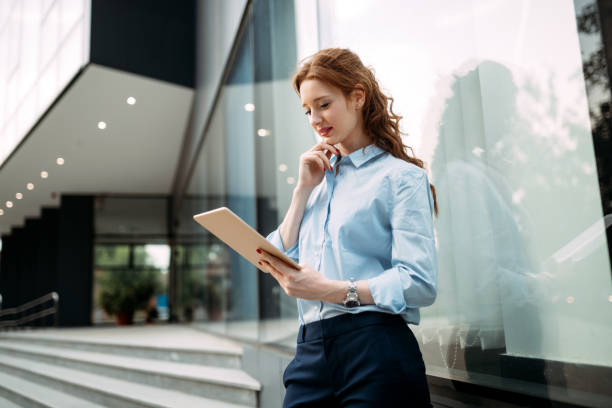istock Attractive young businesswoman using digital tablet outside 875265890