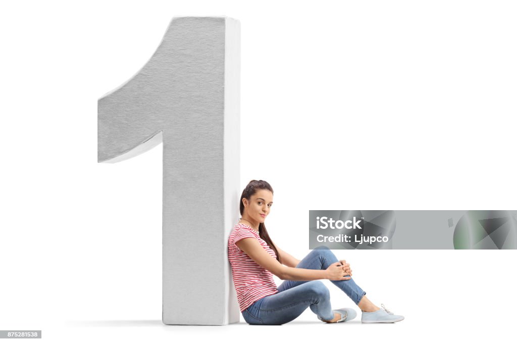 Teenage girl leaning against a cardboard number one Teenage girl leaning against a cardboard number one isolated on white background Leaning Stock Photo