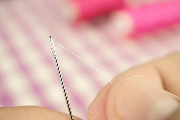 istock Finger hold white thread focus to push through the sewing needle hole 875281674