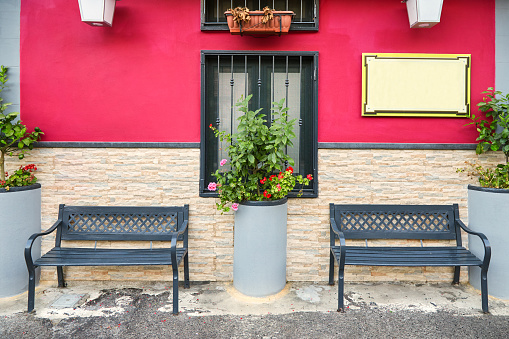 Two empty benches near the beautiful facade of a cafe painted in pink on one of the Italian streets
