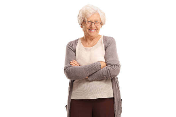 Elderly woman with her arms crossed Elderly woman with her arms crossed looking at the camera and smiling isolated on white background one senior woman only stock pictures, royalty-free photos & images