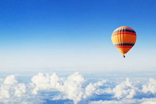 inspiration or travel background, fly above the clouds, colorful hot air balloon in blue sky