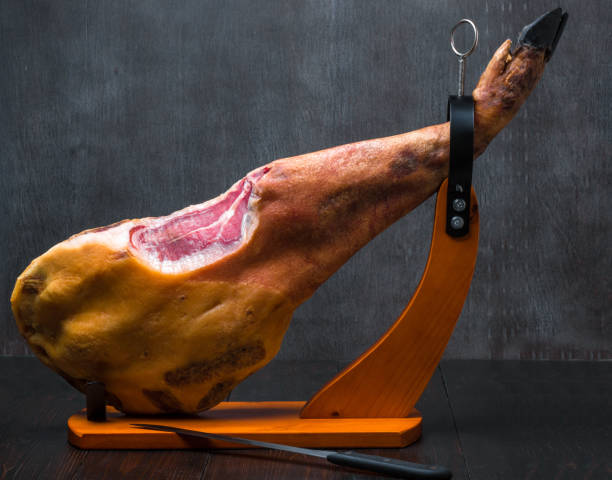 istock Whole mediterranean traditional jamon on a wooden stand with a knife lean on a table. Dark image 875289470